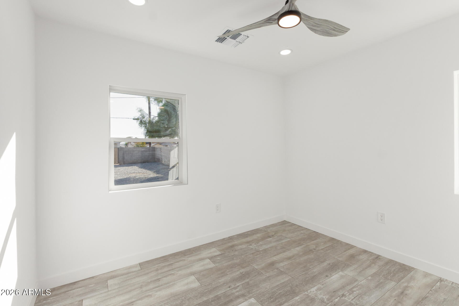9309 West Adams Street Tolleson, AZ 85353 - Photo 17 of 29 an empty room with a window and wooden floor