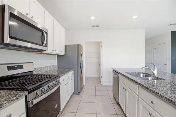 a kitchen with stainless steel appliances granite countertop a sink and a refrigerator