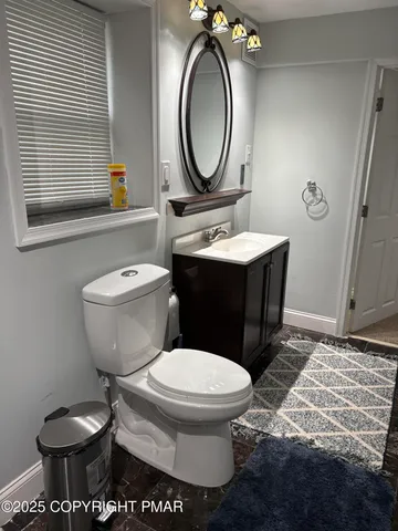a bathroom with a toilet a sink a mirror and a window