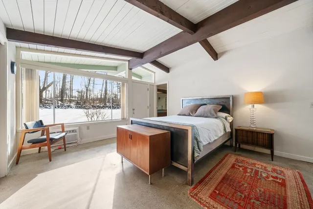 a bed sitting in a spacious bedroom next to a window