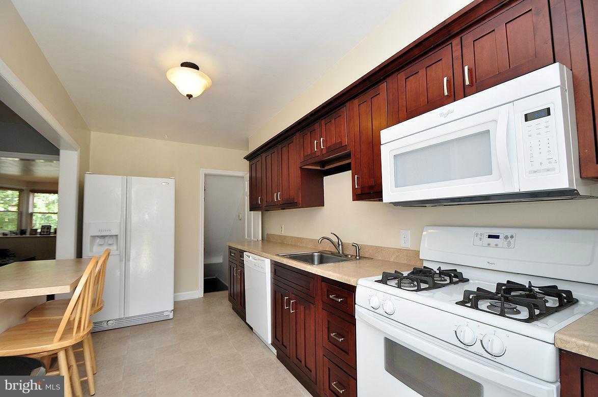 408 Greenlow Road Baltimore, MD 21228 - Photo 11 of 20 a kitchen with stainless steel appliances a stove a sink a refrigerator wooden floor and cabinets