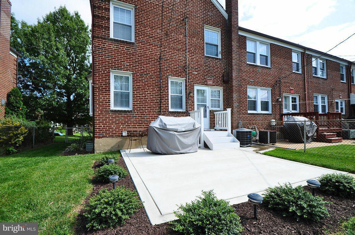 408 Greenlow Road Baltimore, MD 21228 - Photo 3 of 20 a view of a brick house with a yard and table and chairs under an umbrella