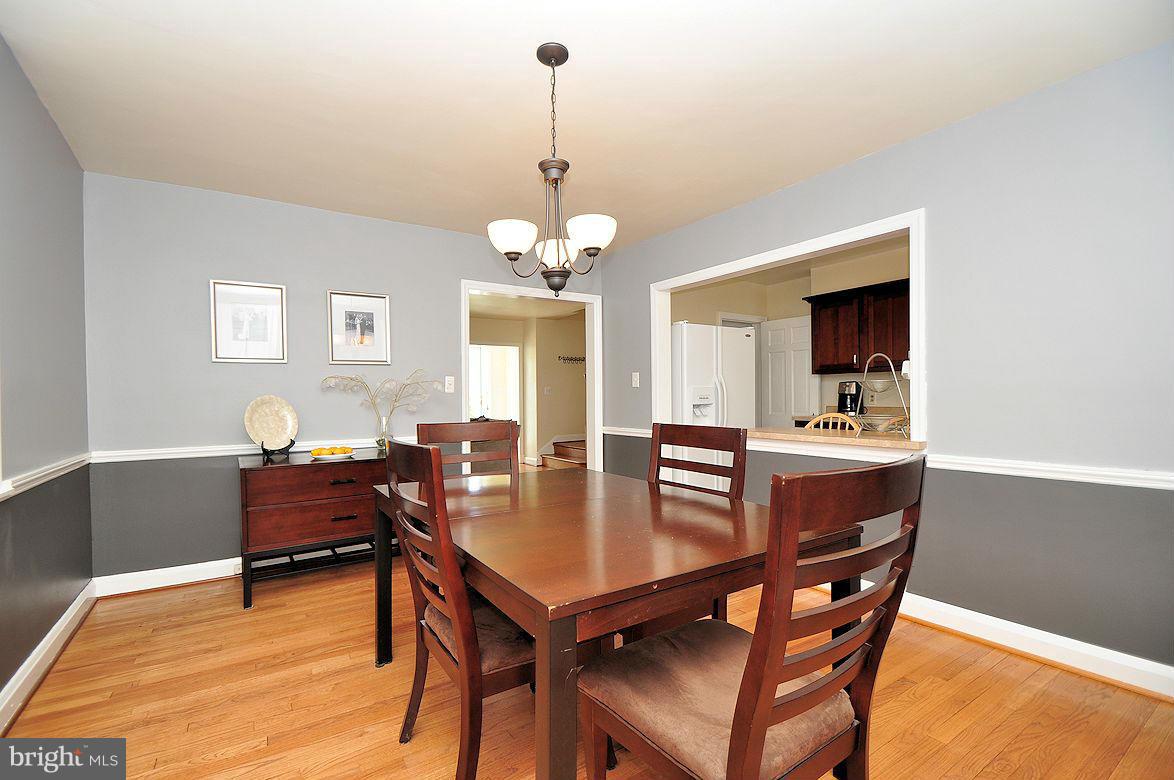 408 Greenlow Road Baltimore, MD 21228 - Photo 9 of 20 a dining room with wooden floor a chandelier a wooden table and chairs