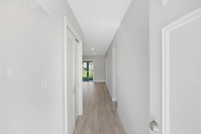 a view of a hallway with wooden floor and a bathroom