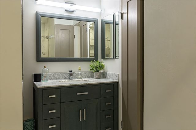 a bathroom with a granite countertop sink vanity and mirror