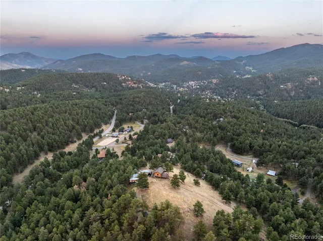 an aerial view of a houses with a lush green hillside