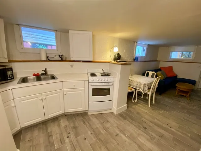 a kitchen with stainless steel appliances kitchen island granite countertop a refrigerator a stove a sink dishwasher and white cabinets with wooden floor