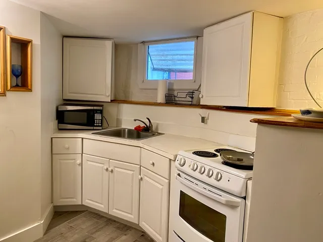 a kitchen with granite countertop a sink a stove and cabinets