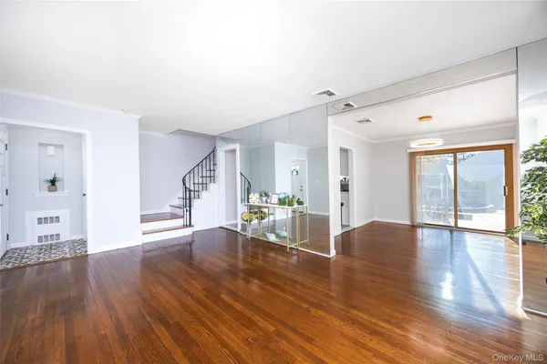 a view of an empty room with window and wooden floor