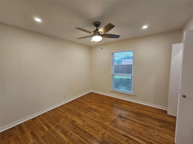 a view of an empty room with a window and wooden floor