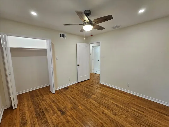 an empty room with wooden floor and a ceiling fan