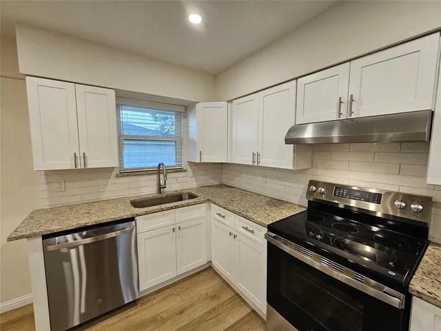 a kitchen with granite countertop a sink stove and cabinets