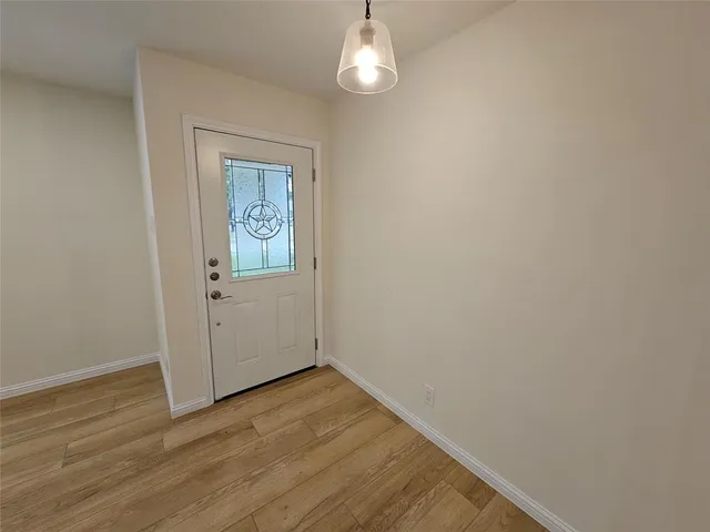 an empty room with wooden floor cabinet and windows