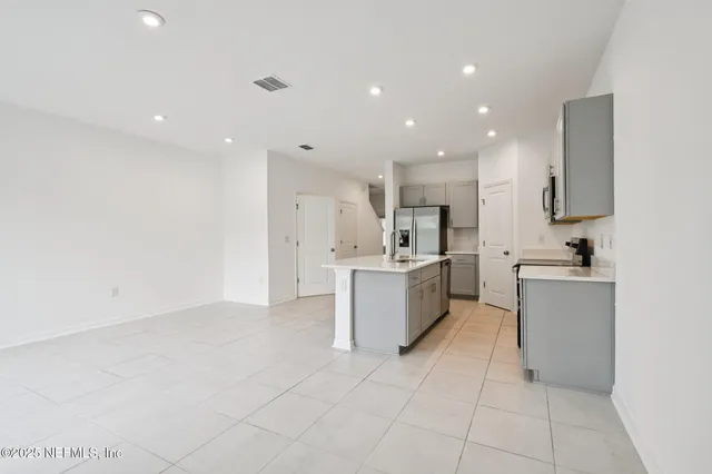 a large kitchen with a large counter top a sink stainless steel appliances and cabinets