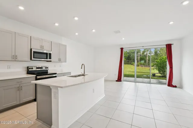 a kitchen with stainless steel appliances granite countertop a sink and a stove top oven with white cabinets