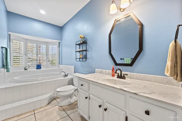 a bathroom with a granite countertop toilet a sink and a mirror