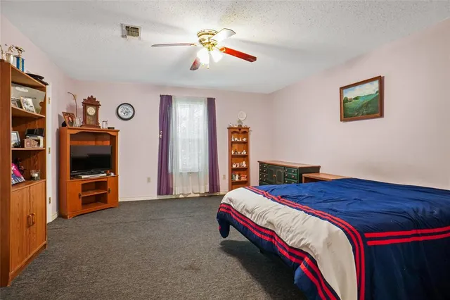 a bedroom with a bed and a flat tv screen on the dresser