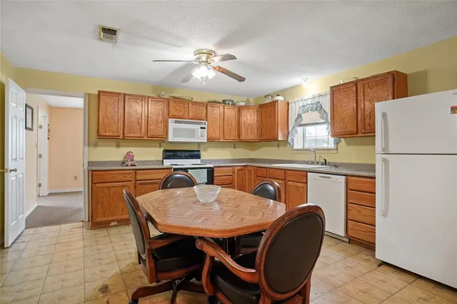 a kitchen with stainless steel appliances granite countertop a dining table chairs refrigerator a sink and dishwasher
