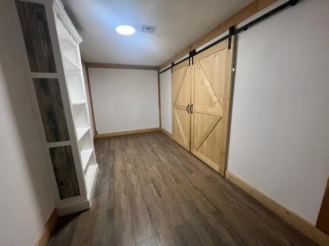 a view of an empty room with wooden floor and closet