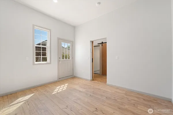 a view of an empty room with wooden floor and a window