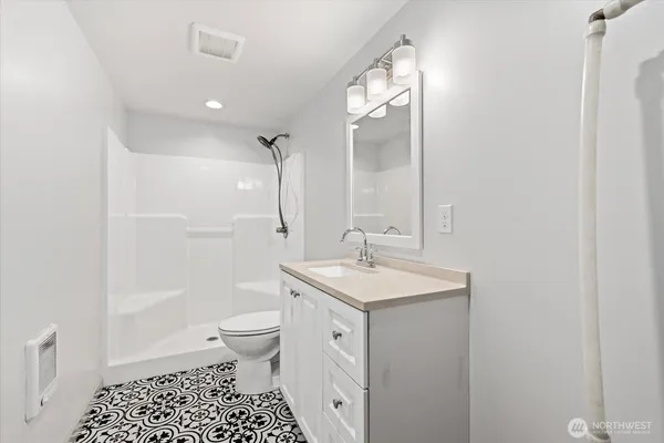 a spacious bathroom with a sink a toilet a shower and a mirror