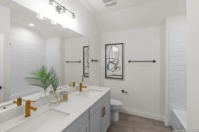 a bathroom with a granite countertop sink a toilet and a large mirror