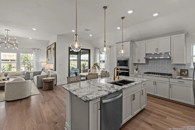 a kitchen with granite countertop kitchen island stainless steel appliances a stove a sink a oven a dining table and chairs