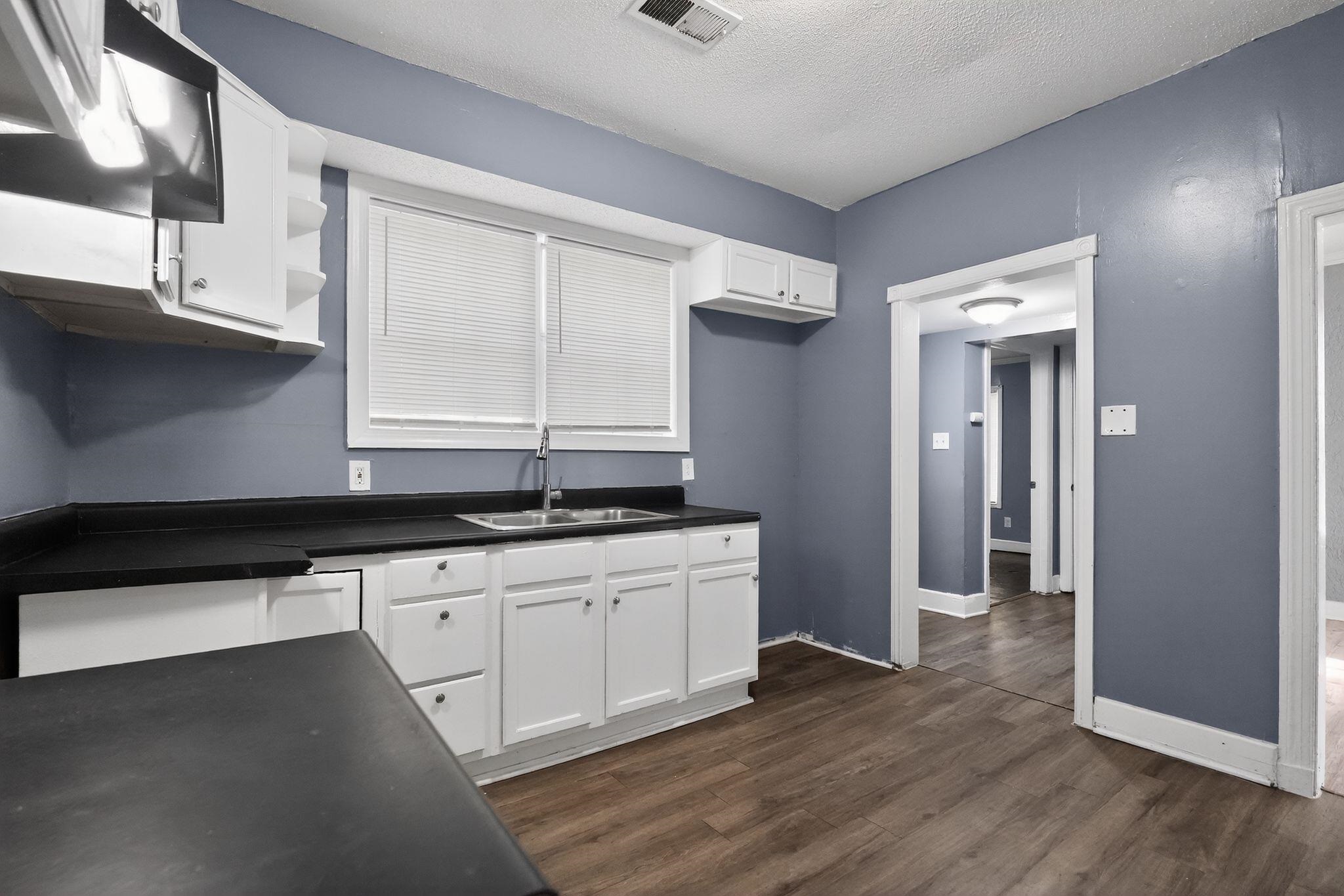 4199 Auburn Road Memphis, TN 38116 - Photo 20 of 32 Kitchen featuring wood-finish flooring, white cabinetry, dark countertops, and a stainless steel sink with a single-handle faucet