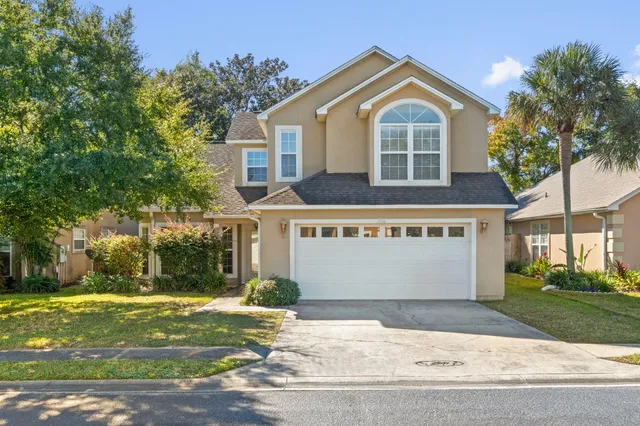 a front view of a house with a garden and trees