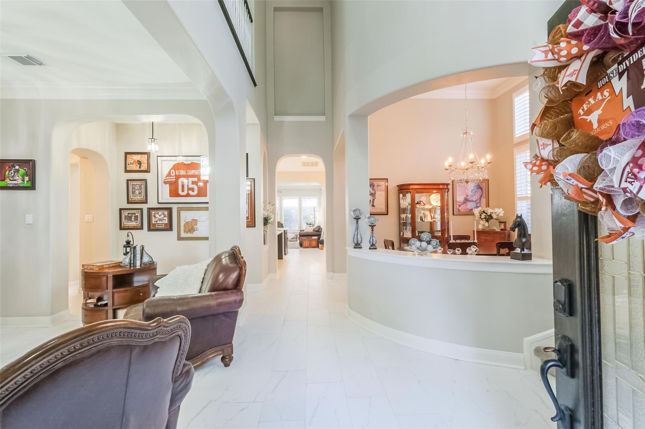 11413 Gallant Ridge Lane Houston, TX 77082 - Photo 14 of 50 Welcome to a spacious, bright entryway with high ceilings and elegant archways. The open layout features a stylish sitting area, decorative wall art, and a glimpse into a formal dining room adorned with a chandelier. Perfect for a warm, inviting home.