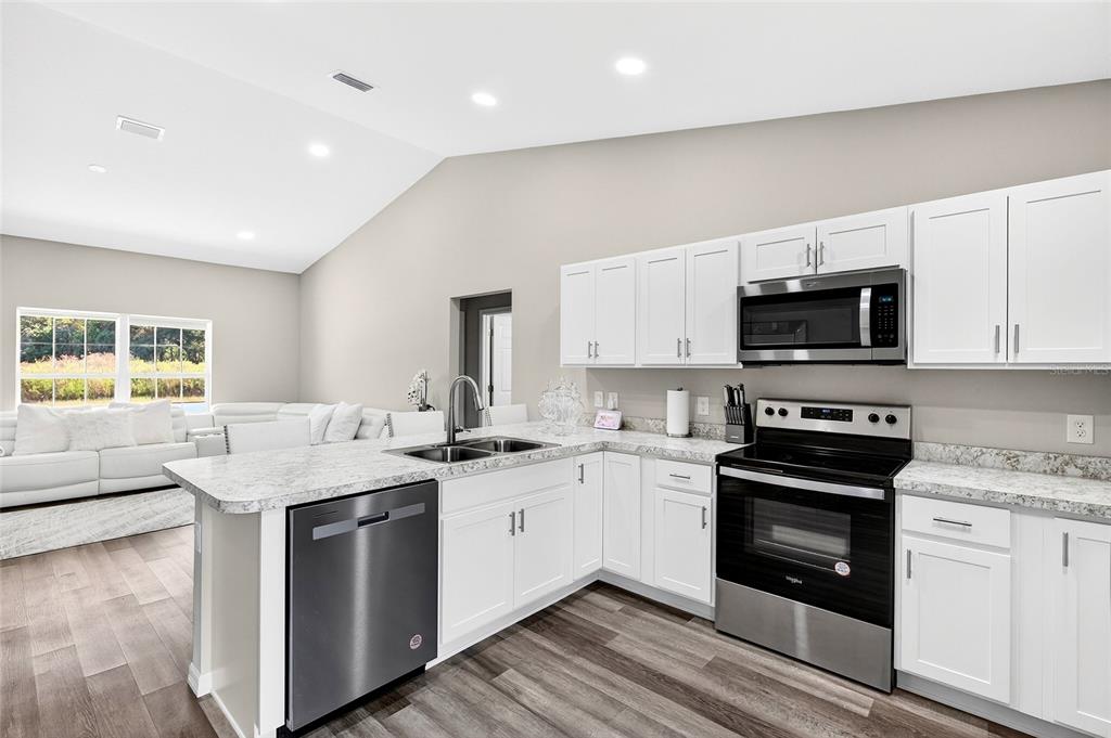 14862 Southwest 79 Terrace Road Dunnellon, FL 34432 - Photo 10 of 28 a kitchen with granite countertop a sink stainless steel appliances and white cabinets