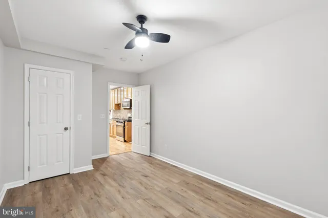 a view of empty room with wooden floor and ceiling fan
