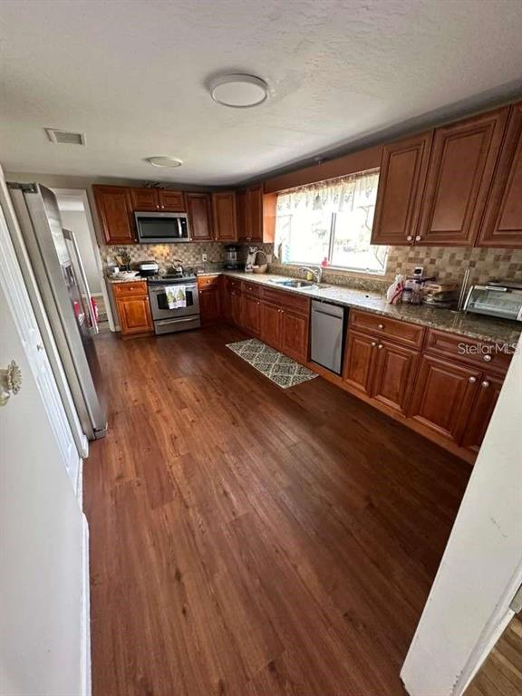 1509 Tate Street Cocoa, FL 32922 - Photo 3 of 12 a kitchen with stainless steel appliances wooden floors and wooden cabinets