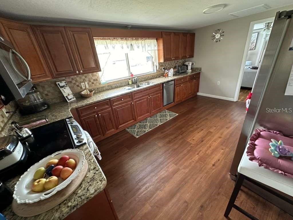 1509 Tate Street Cocoa, FL 32922 - Photo 4 of 12 a kitchen with granite countertop a stove a sink and wooden floor