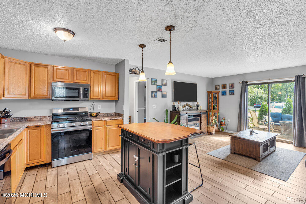 1506 Jasmine Court Jackson, NJ 08527 - Photo 6 of 20 a open kitchen with stainless steel appliances granite countertop a stove top oven a sink dishwasher a dining table and chairs with wooden floor