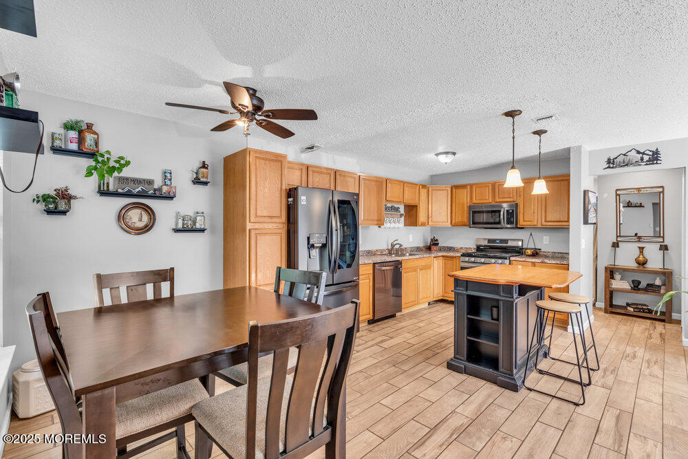 1506 Jasmine Court Jackson, NJ 08527 - Photo 8 of 20 a kitchen with stainless steel appliances a stove a refrigerator a kitchen island a dining table and chairs with wooden floor