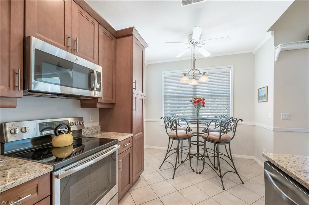 917 Fairhaven Court, Unit 29 Naples, FL 34104 - Photo 11 of 40 a kitchen with stainless steel appliances kitchen island granite countertop a table chairs in it and wooden cabinets