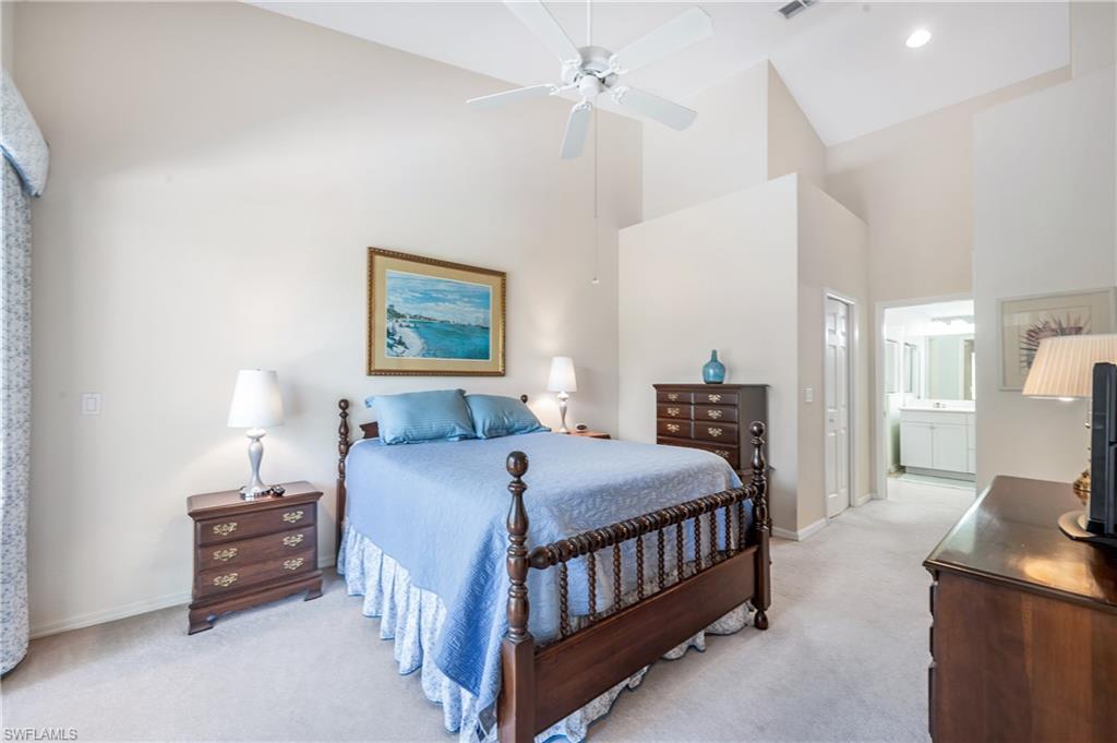 917 Fairhaven Court, Unit 29 Naples, FL 34104 - Photo 14 of 40 a bedroom with a bed a chandelier and a dresser