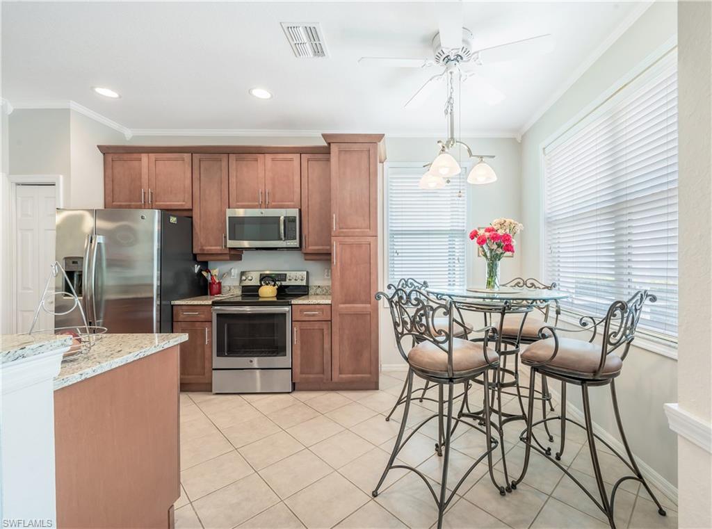 917 Fairhaven Court, Unit 29 Naples, FL 34104 - Photo 8 of 40 a kitchen with granite countertop a dining table chairs stainless steel appliances and cabinets
