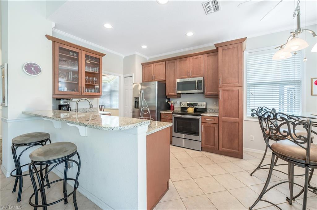 917 Fairhaven Court, Unit 29 Naples, FL 34104 - Photo 9 of 40 a kitchen with stainless steel appliances a refrigerator a stove a sink dishwasher and a dining table with wooden cabinet