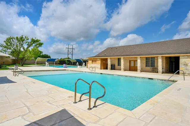 a view of swimming pool that has lawn chairs under an umbrella