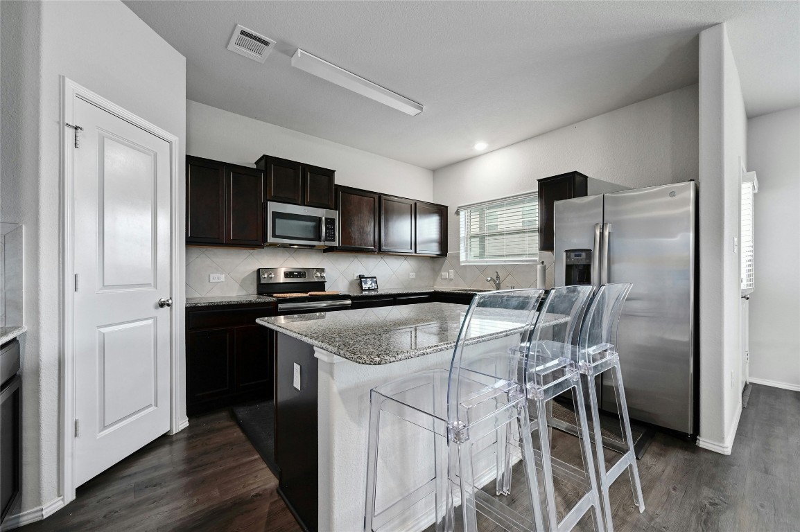 100 Comet Drive, Unit 1I Jarrell, TX 76537 - Photo 3 of 25 a kitchen with stainless steel appliances granite countertop a refrigerator stove microwave and sink