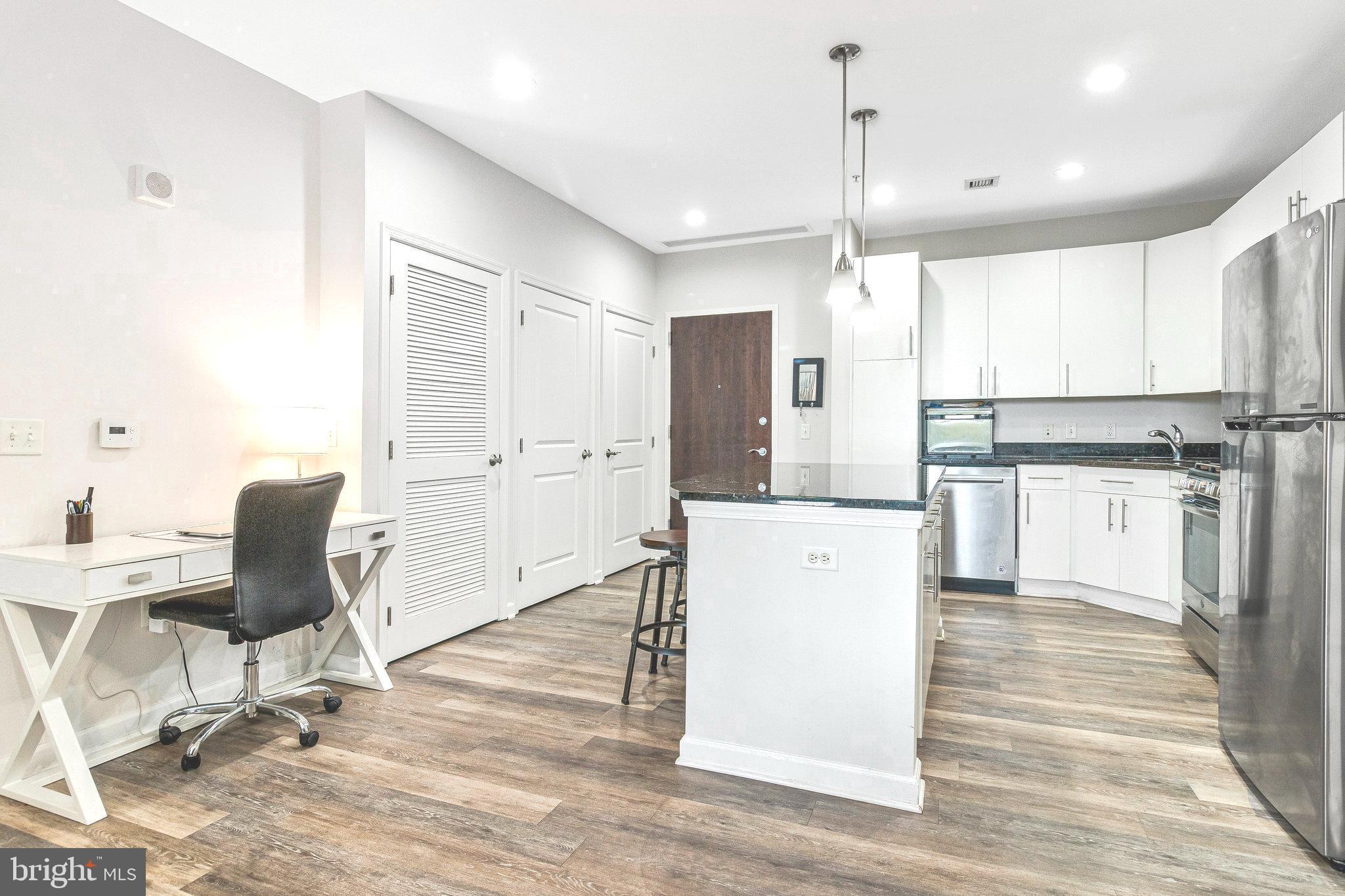 444 West Broad Street, Unit 401 Falls Church, VA 22046 - Photo 7 of 43 a kitchen with kitchen island white cabinets and white appliances