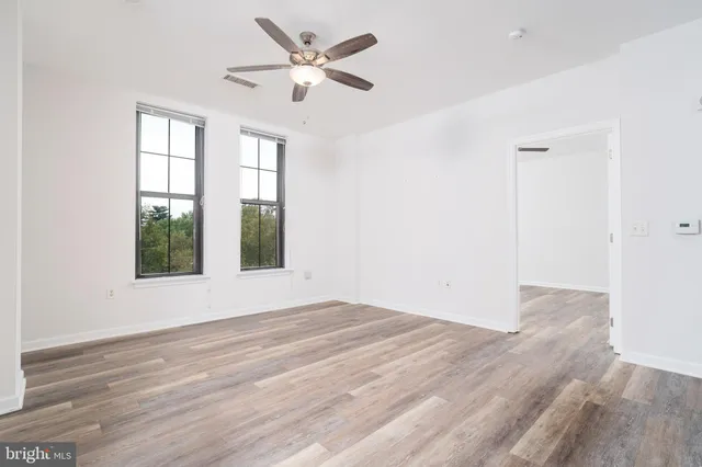 a view of an empty room with wooden floor and a window