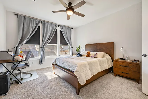 a bedroom with a bed a couch and a ceiling fan