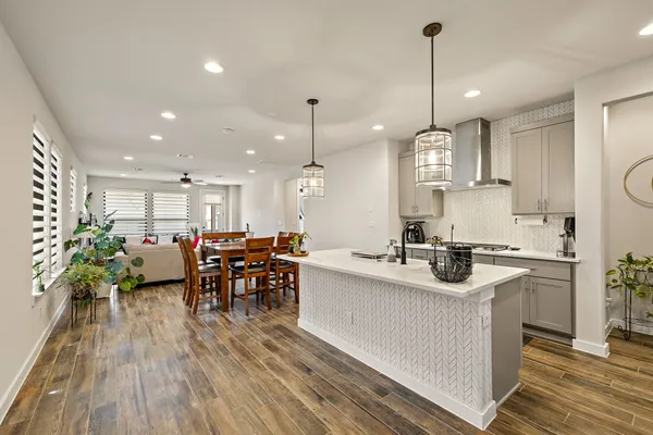 a kitchen with stainless steel appliances a sink a stove top oven a kitchen island with furniture