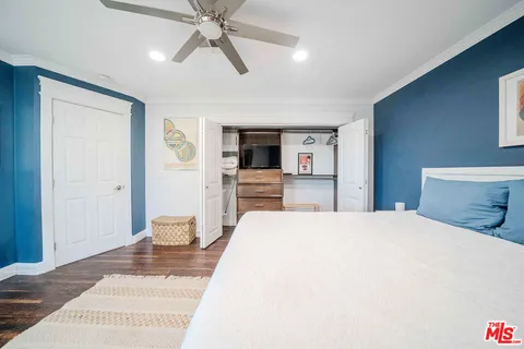 a spacious bedroom with a bed and a flat tv screen on dresser