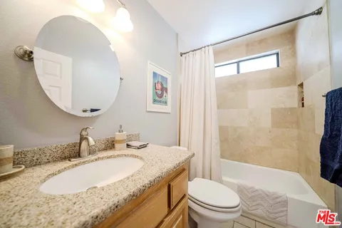 a bathroom with a granite countertop sink toilet and shower