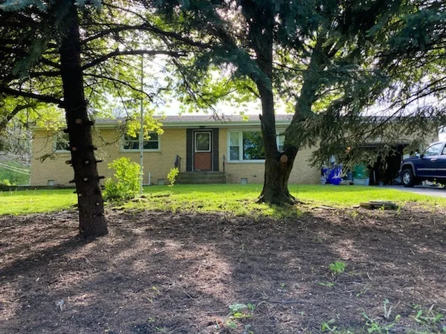 a view of a house with a yard and large trees