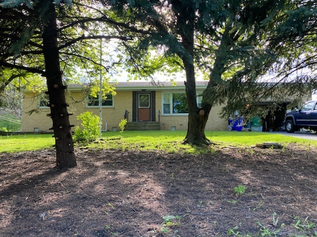 a view of a house with a yard and large trees